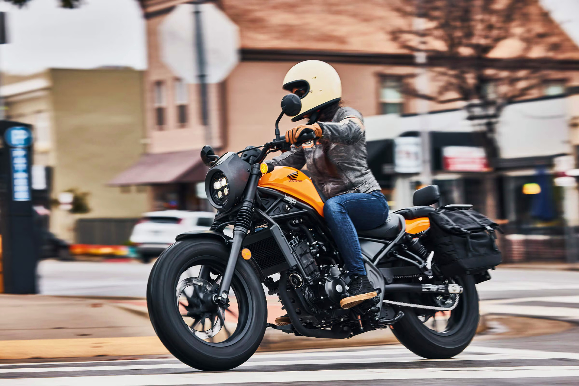 Honda Rebel 300 with rider cornering on a city street left side view.