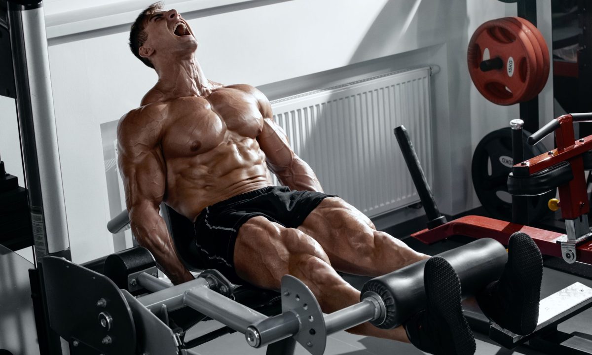 Man doing leg curl exercise on gym seated machine
