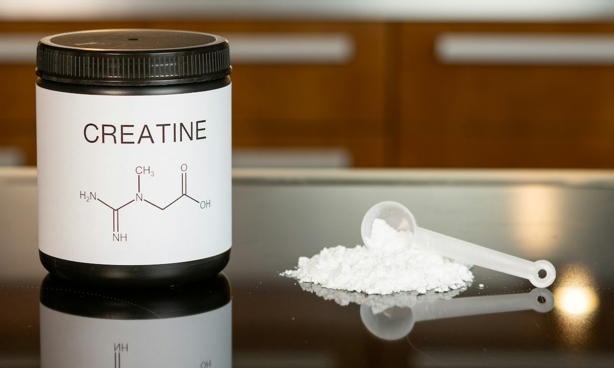 Creatine powder with some on table with a spoon
