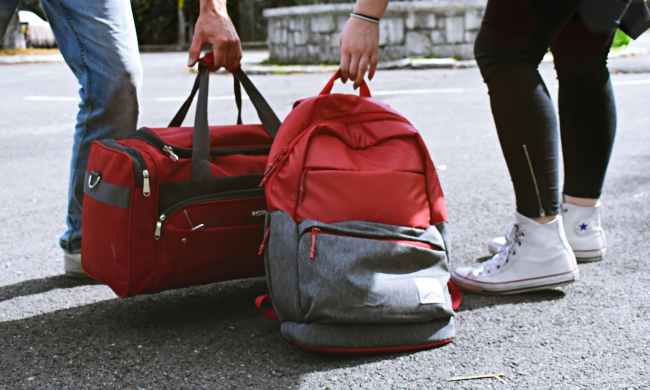 someone carrying a duffel bag and someone carrying a backpack next to each other