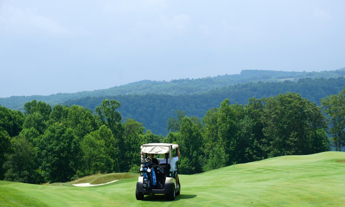 People riding a golf cart around the gofl course