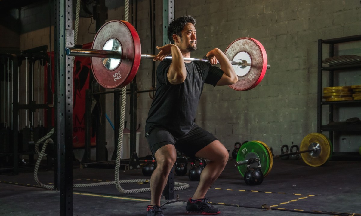 red weights Athletic man having workout and bodybuilding with barbells weight front squat setting style in gym and fitness club in dark tone