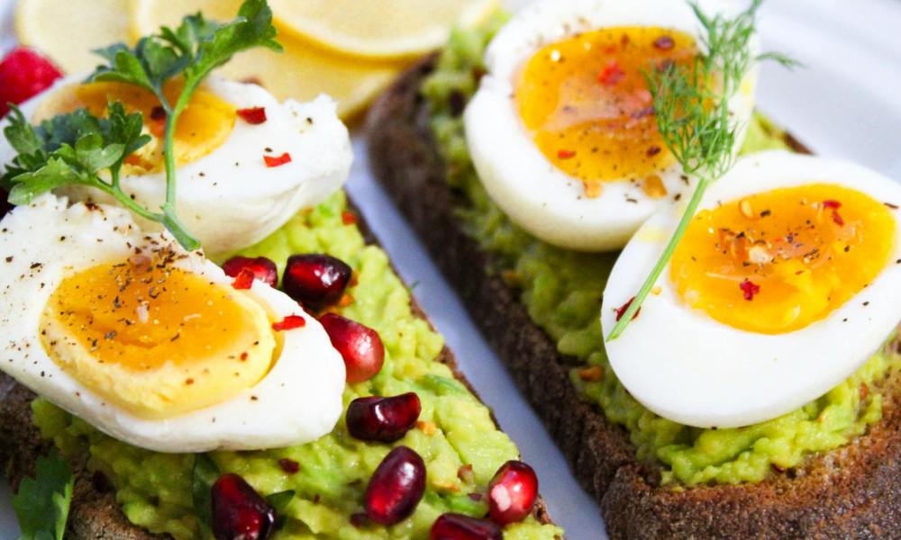 Boiled eggs sliced on avocado toast