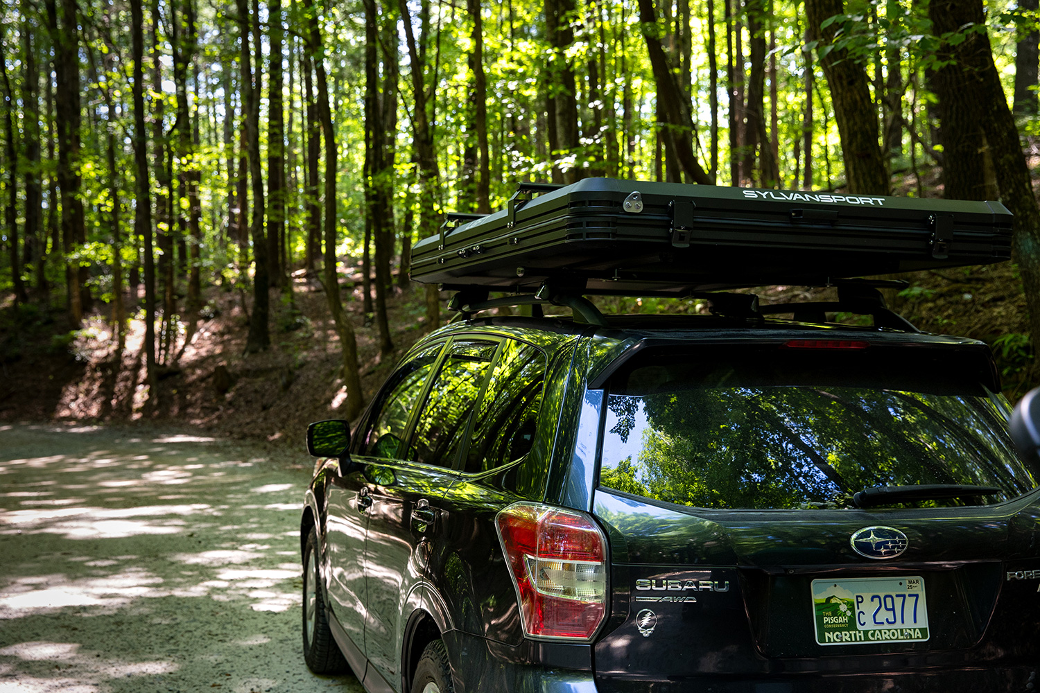 SylvanSport's 2025 Loft Rooftop Tent mounted to the top of a Subaru parked in the woods