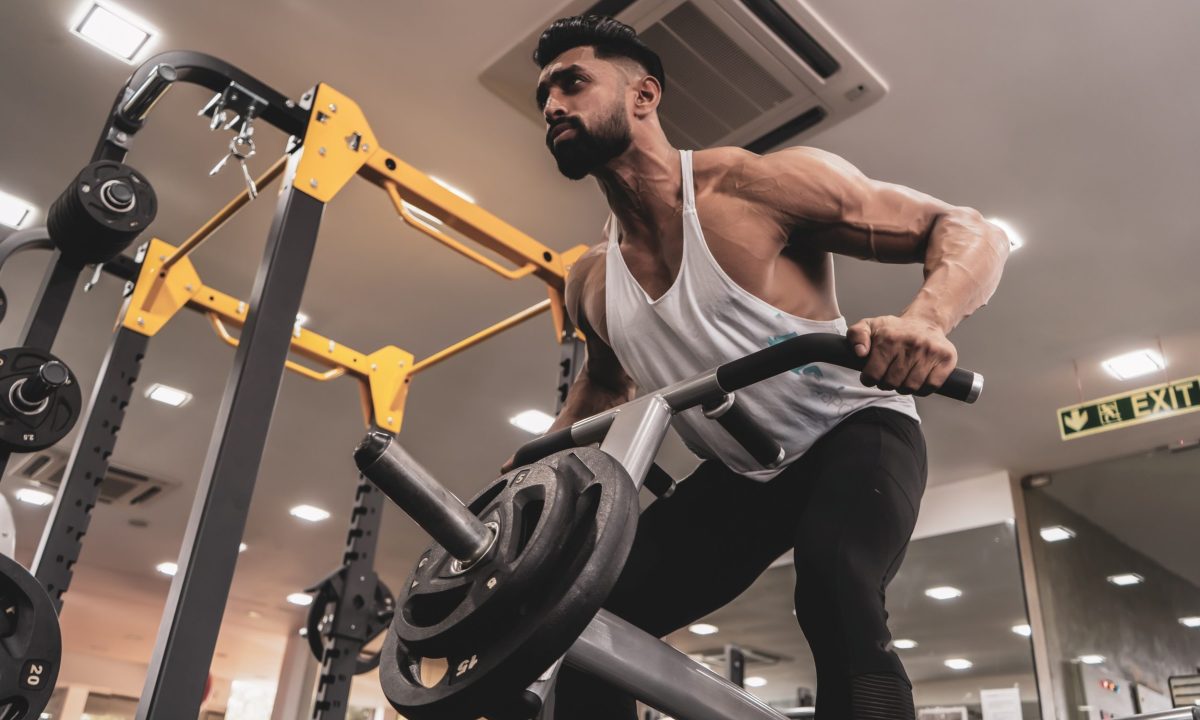 Guy in gym using machine to do the T-bar row exercise