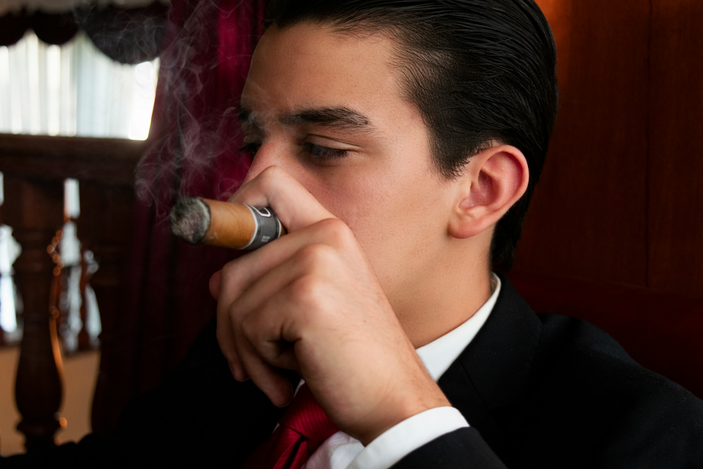 Man in suit smoking cigar in a lounge, relaxing.