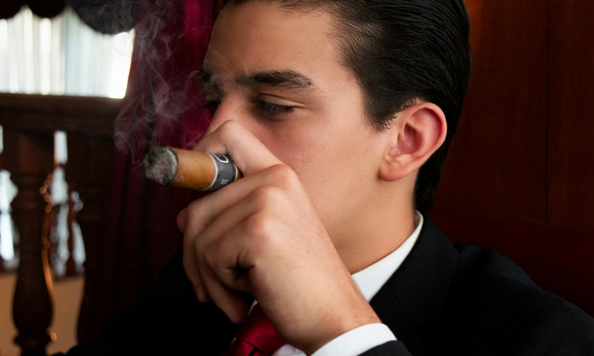 Man in suit smoking cigar in a lounge, relaxing.
