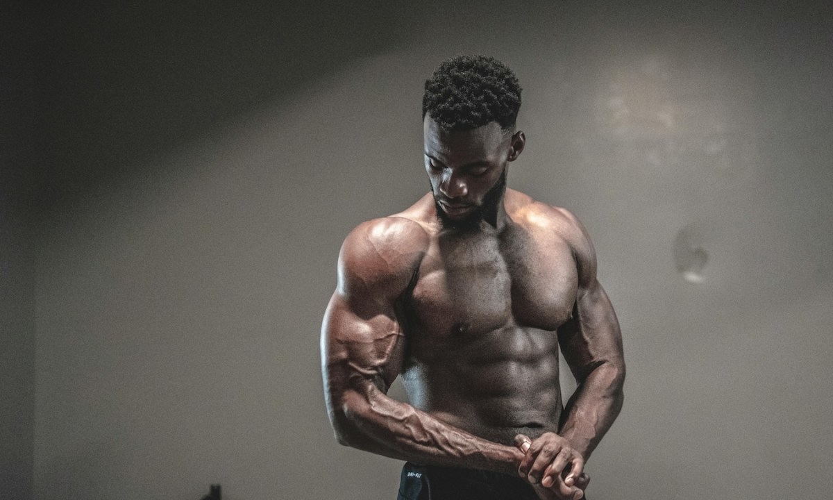 a man with a 6 pack standing against a wall with a shadow.