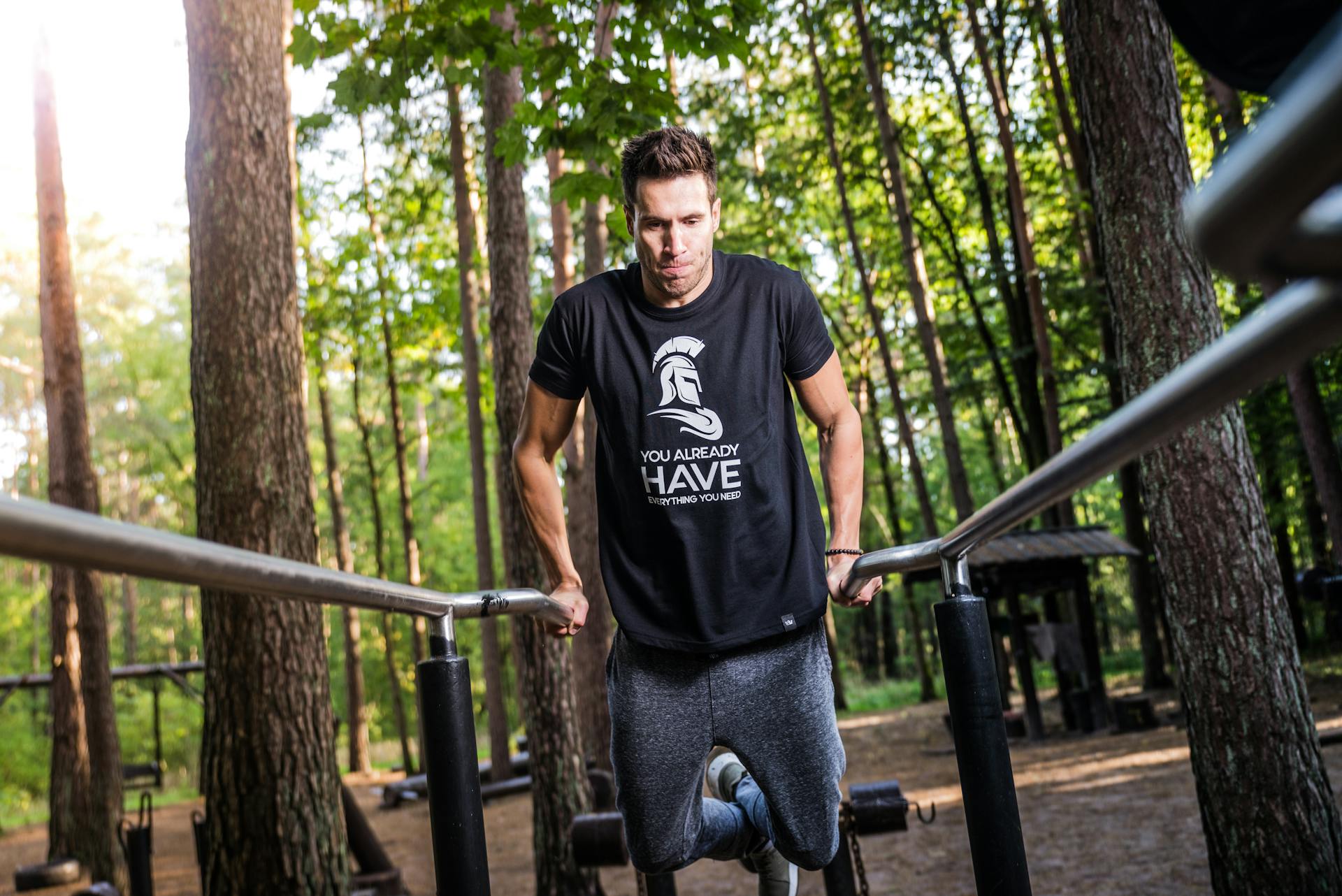 Man working out outside on dip bars exercise bars doing chest dips black t shirt