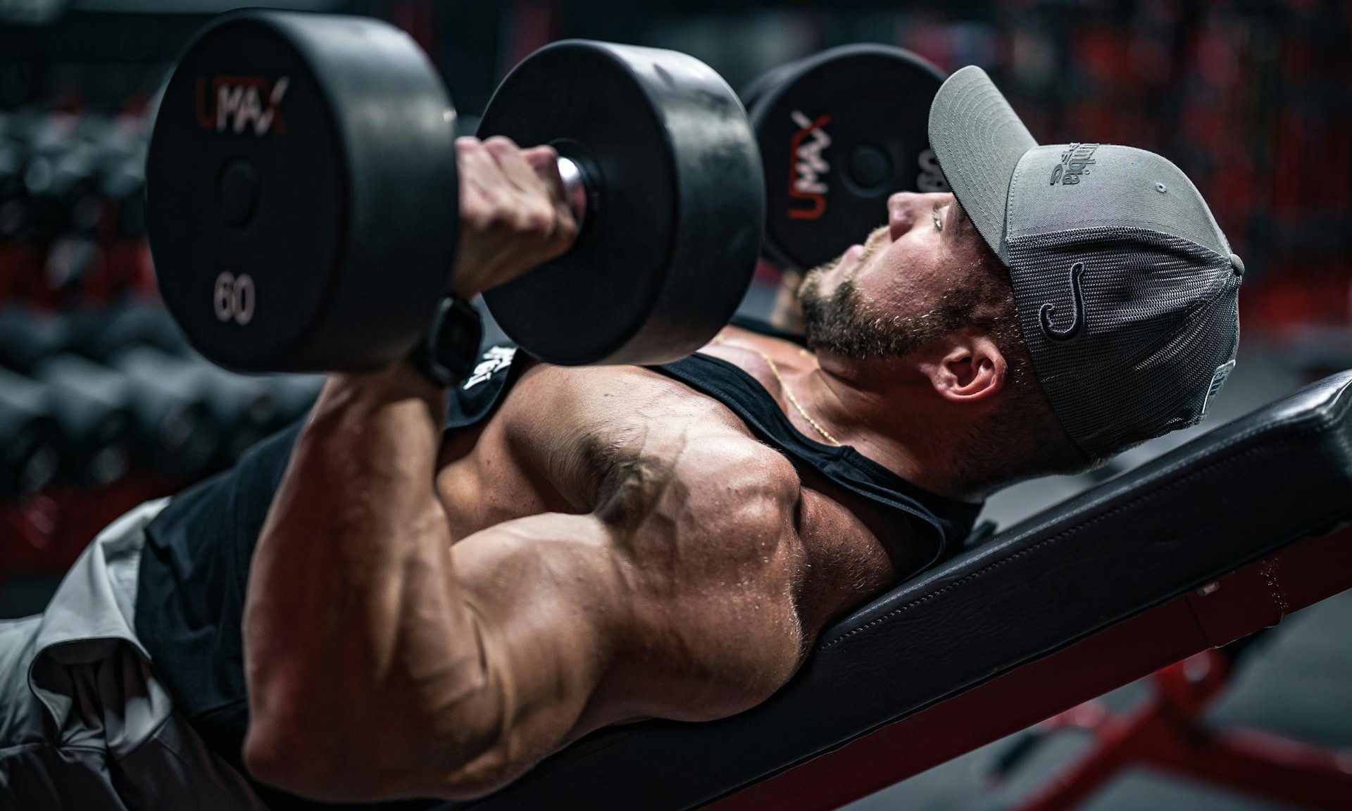 Man laying on workout bench doing chest presses with dumbbells