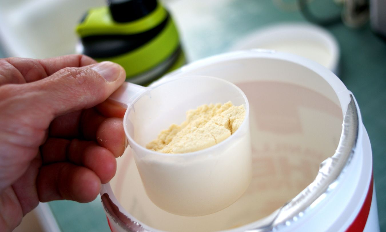 Person scooping protein powder out of canister