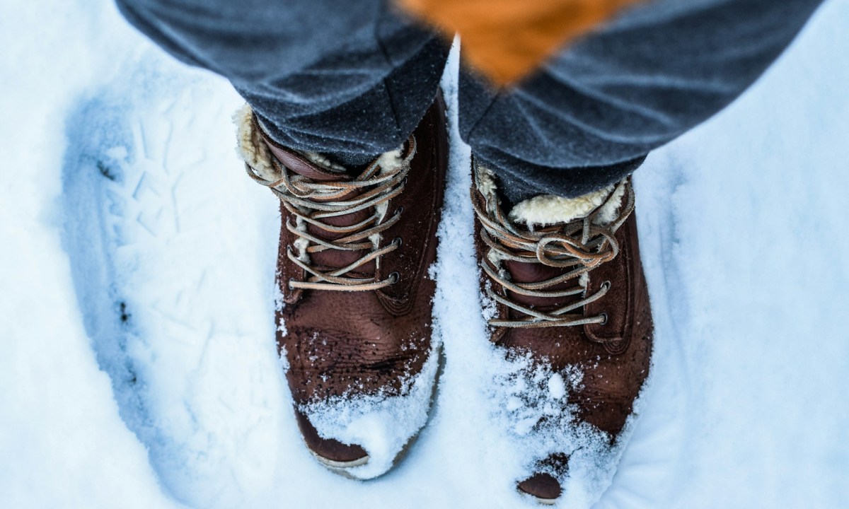 Closeup of man's feet wearing insulated winter boots in the snow.