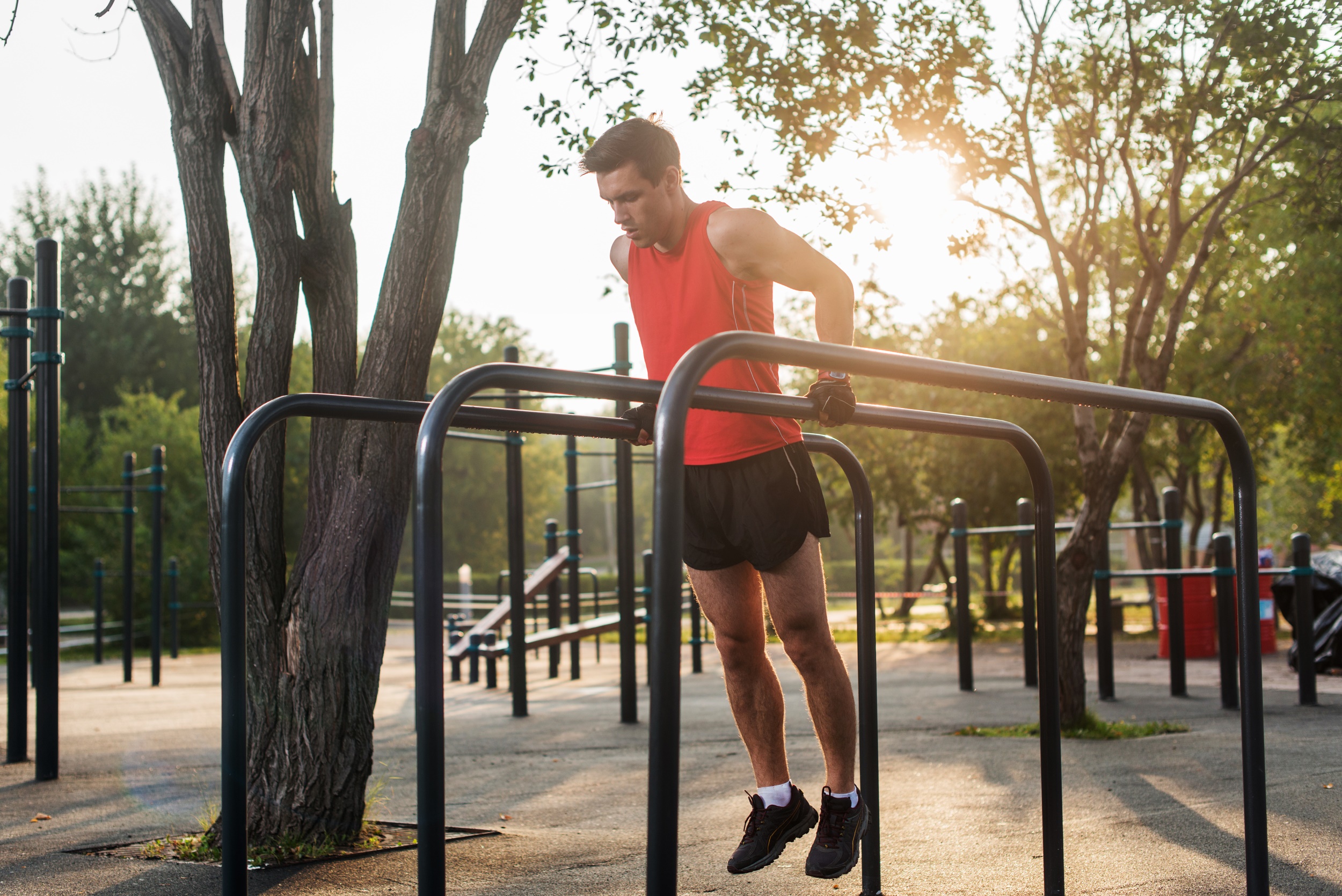 Man working out doing chest dips on parallel bars outside
