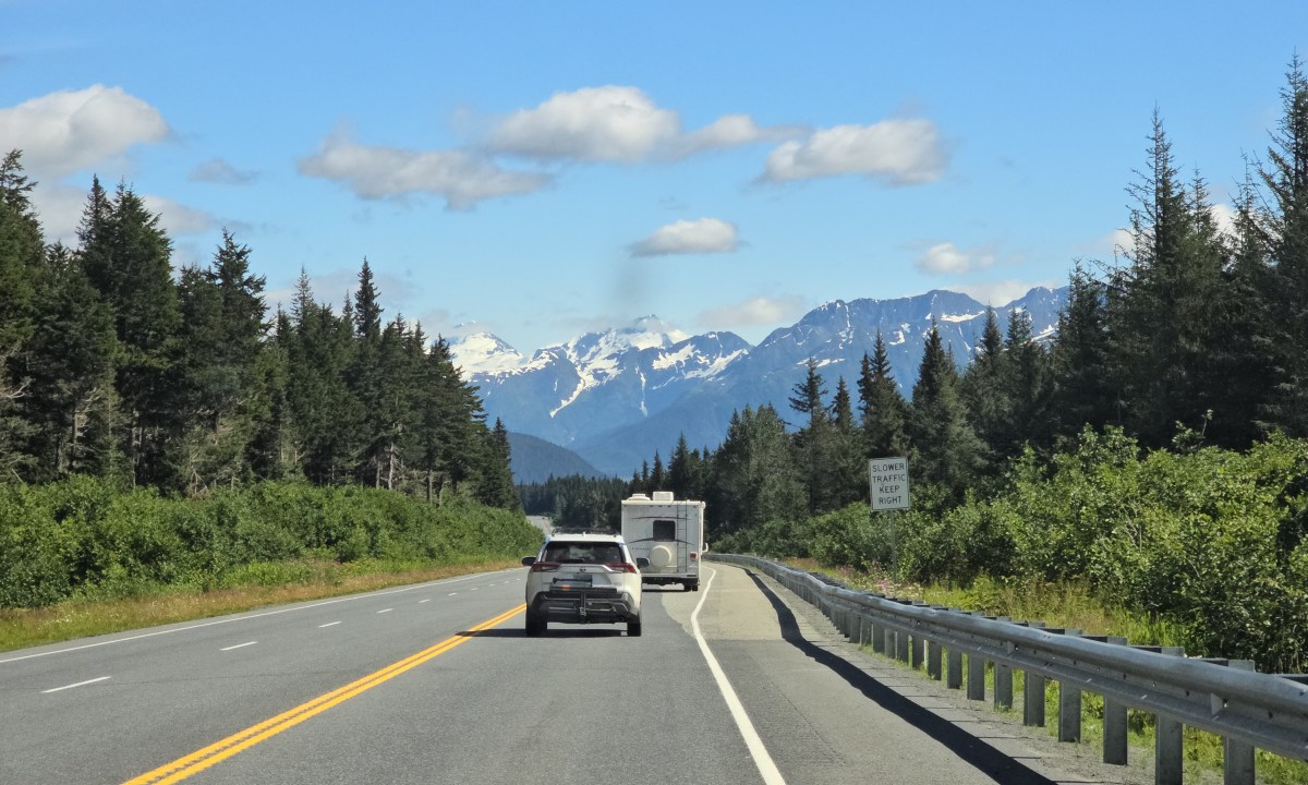 A road leading to Alaska with mountains in the background