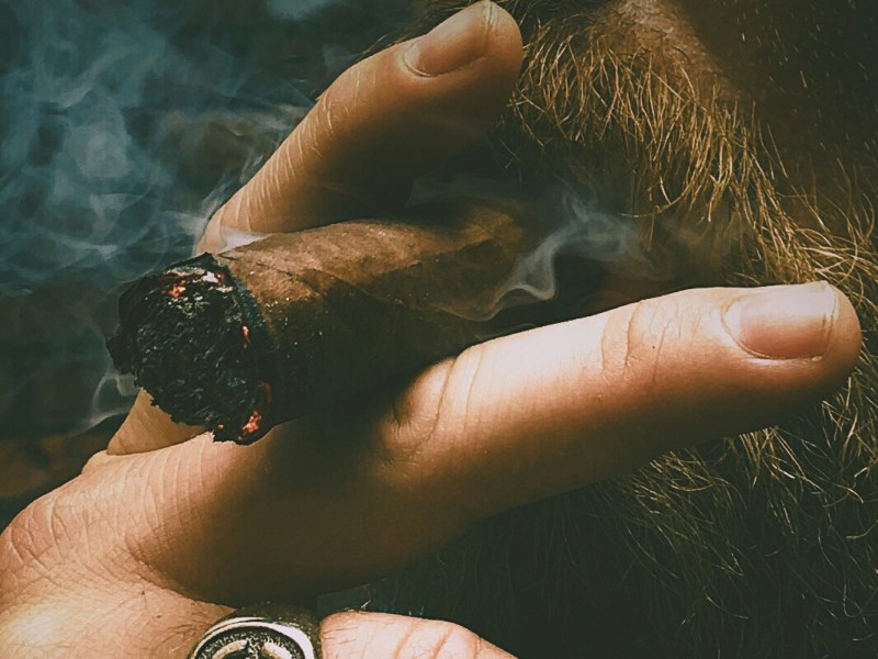 Bearded man smoking, possibly one of the best sweet cigars.
