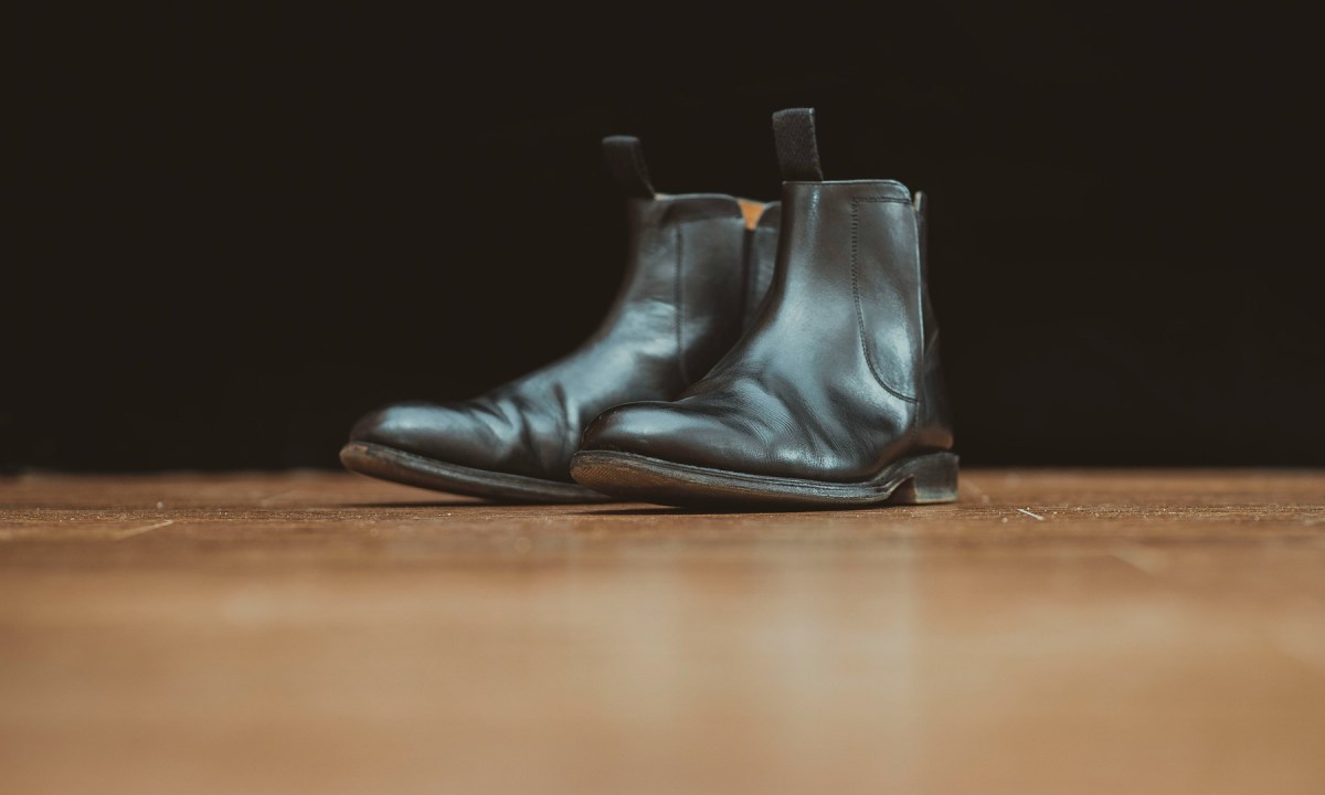 black chelsea boots sitting on wood floor