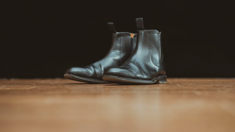 black chelsea boots sitting on wood floor