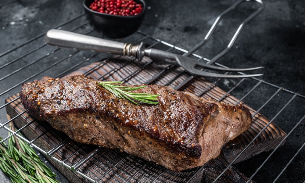 BBQ grilled tri-tip beef steak on a grill. Black background