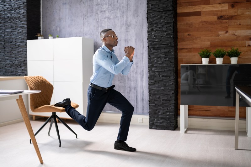 Man exercising in the office at work Bulgarian split squat