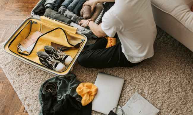 A man packing shoes in his suitcase