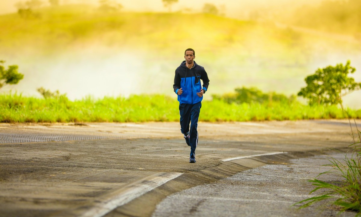 man wearing black and blue jacket running outdoors in nature