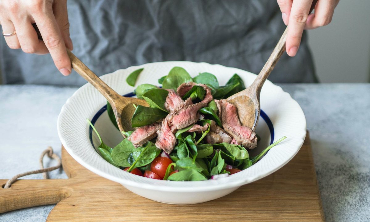 Person tossing steak salad