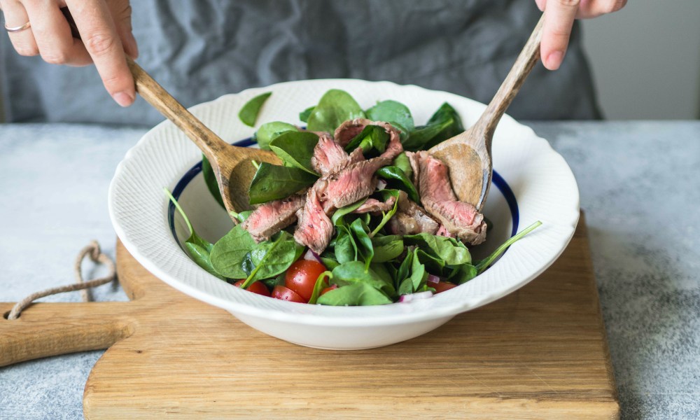 Person tossing steak salad