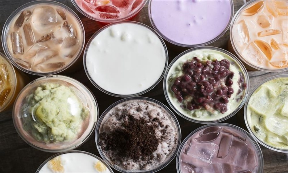 Ube latte, a top down view of a background of several varieties of milk tea beverages