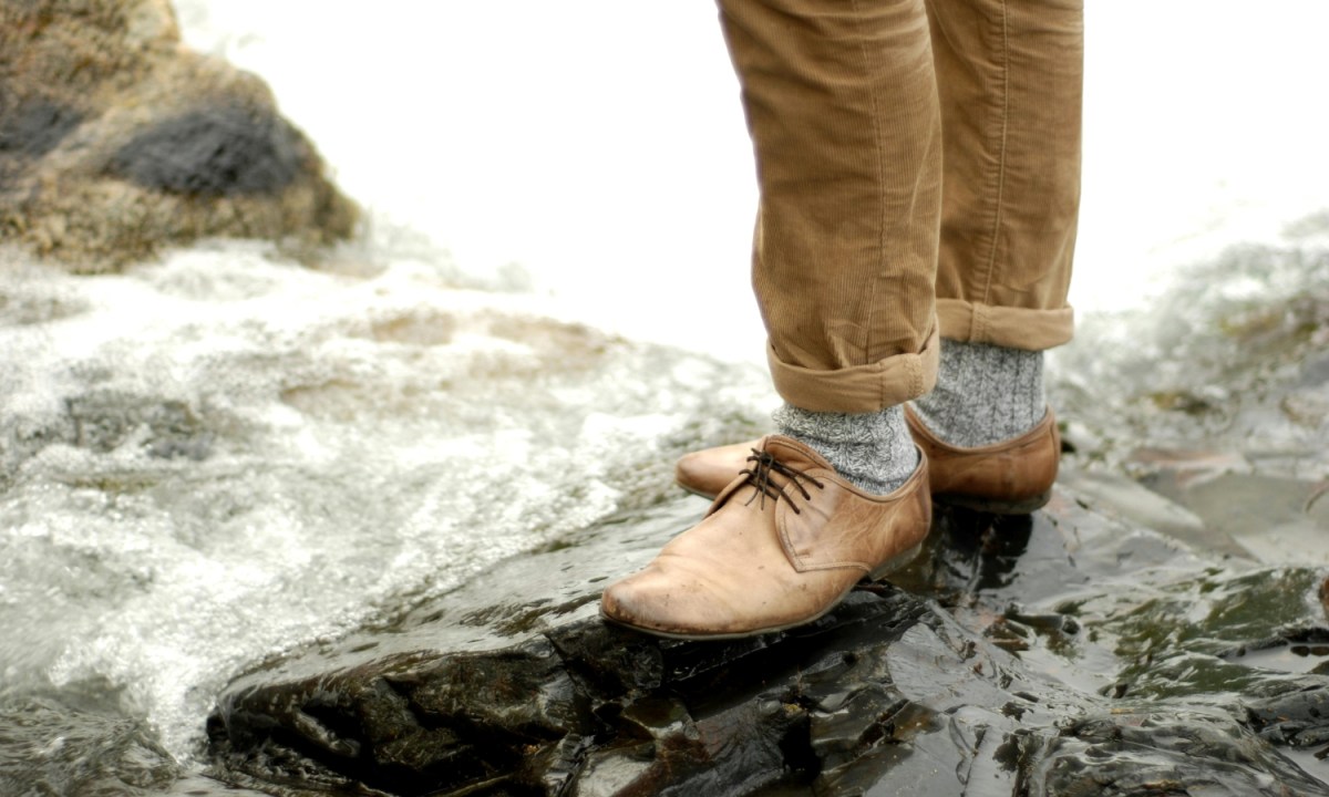 Man in corduroy pants standing on a rock in a river