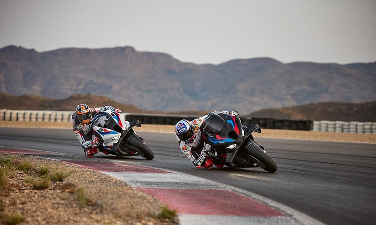 Two 2025 BMW M 1000 RR motorcycles leaning hard into a race track corner.