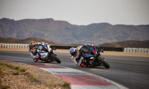 Two 2025 BMW M 1000 RR motorcycles leaning hard into a race track corner.
