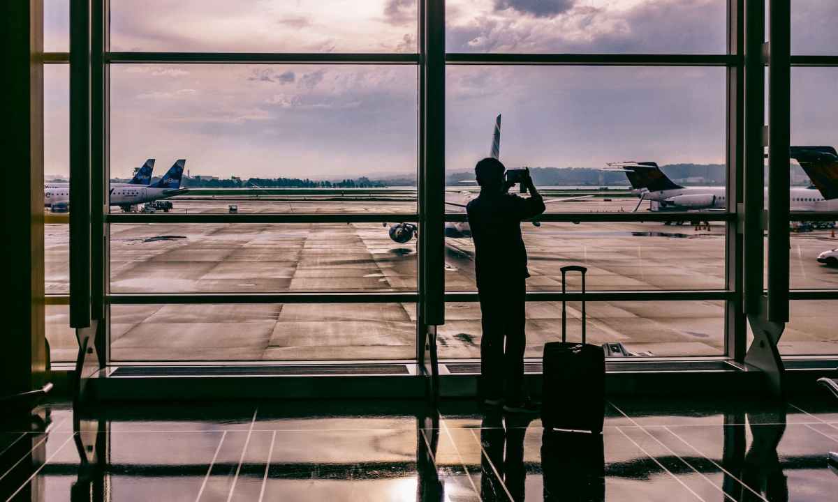 man taking photo of airplanes from inside airport
