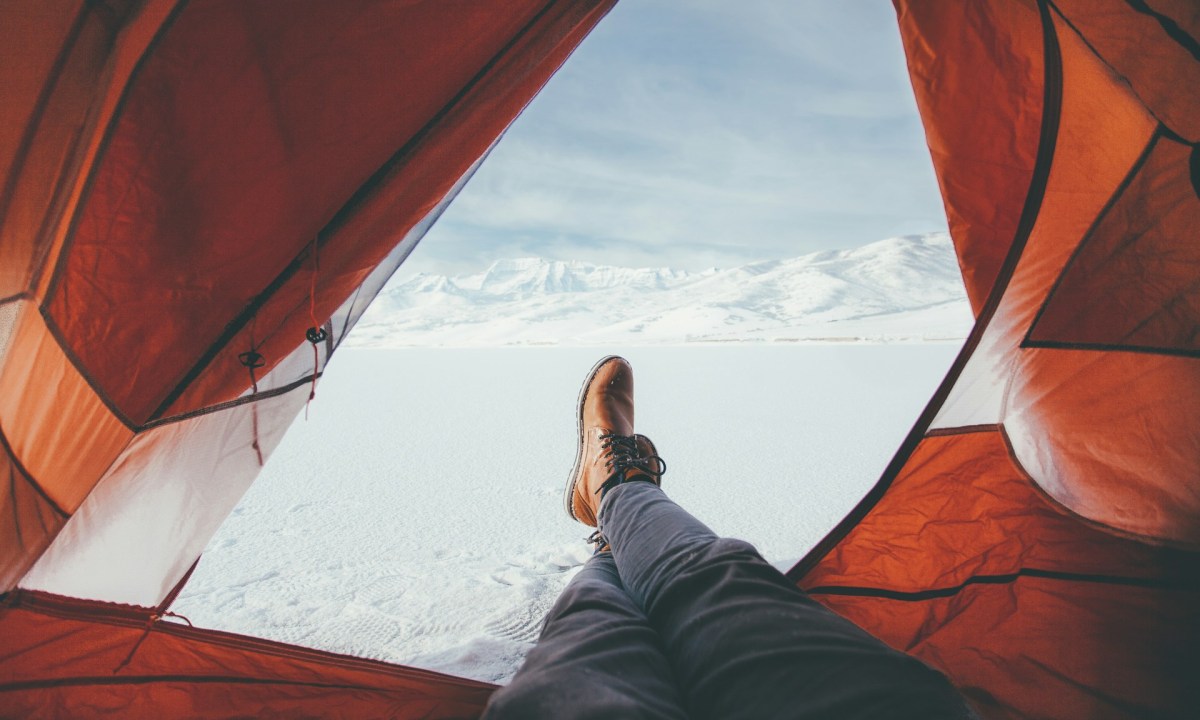 Hiker relaxing in his tent with a great view of the snowy mountains