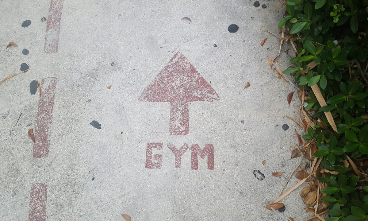 Gym sign on road in red concrete with arrow pointing to gym