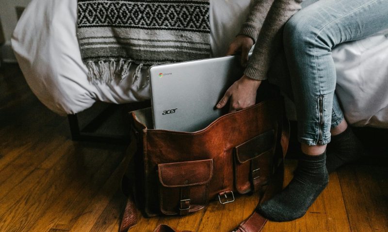 person packing a laptop in a bag