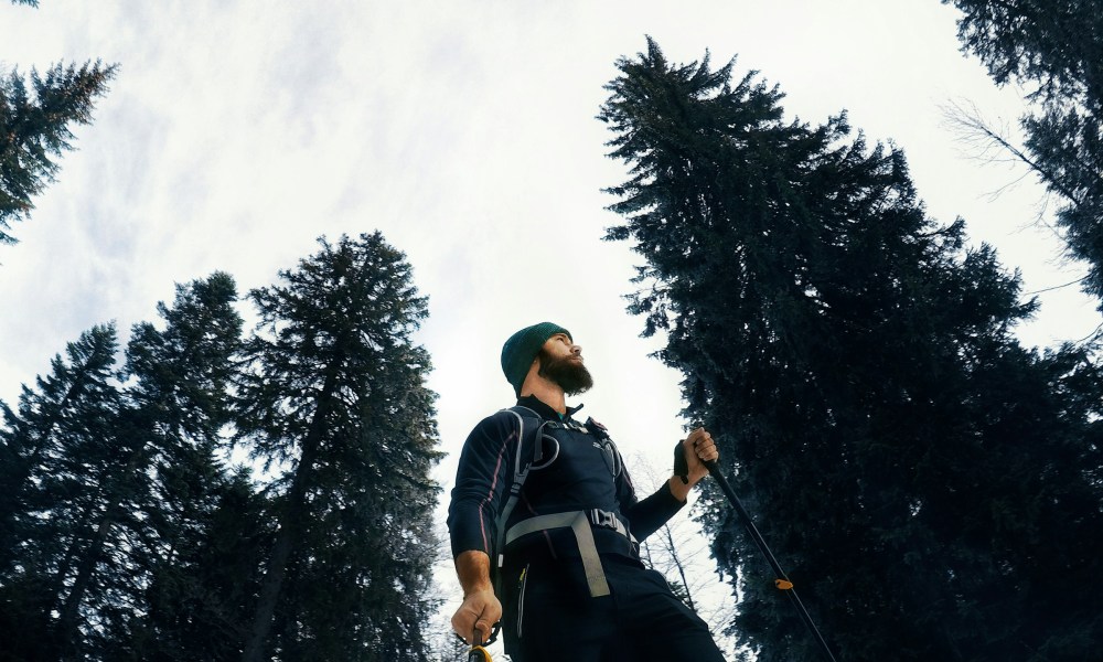 Man walking with Nordic walking poles outside by the trees wearing a hat