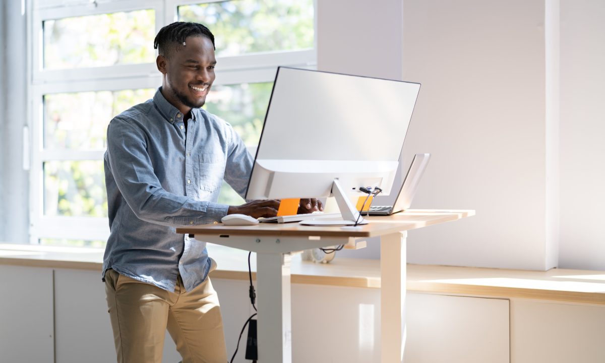 Man using adjustable height standing desk In office for good posture