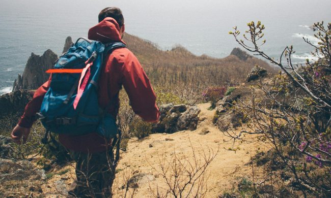 Man wearing red and backpack rucksack rucking hiking walking in nature outdoors