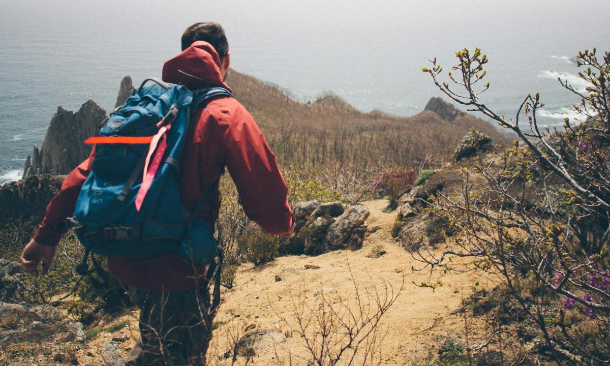 Man wearing red and backpack rucksack rucking hiking walking in nature outdoors