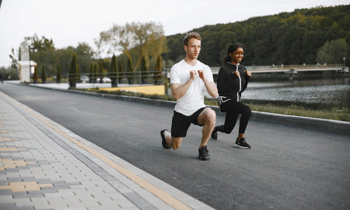 Man and woman doing walking lunges outside