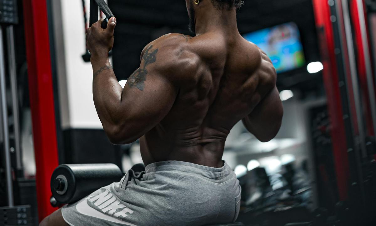 shirtless man in gym doing close grip lat pulldown with cable machine