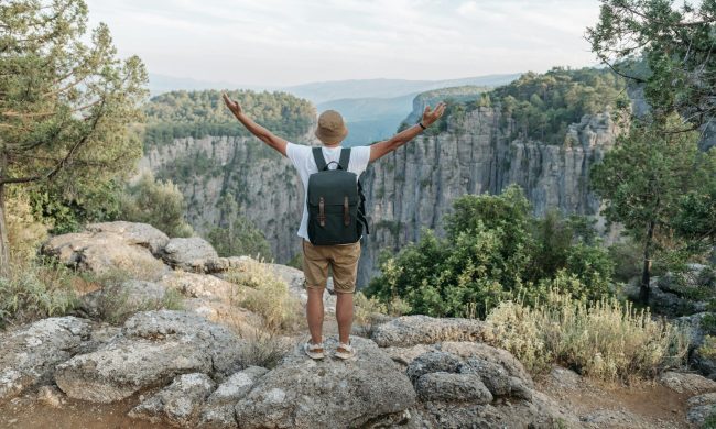 Man arms out exercise happy on rocks mountains nature rucking backpack rucksack