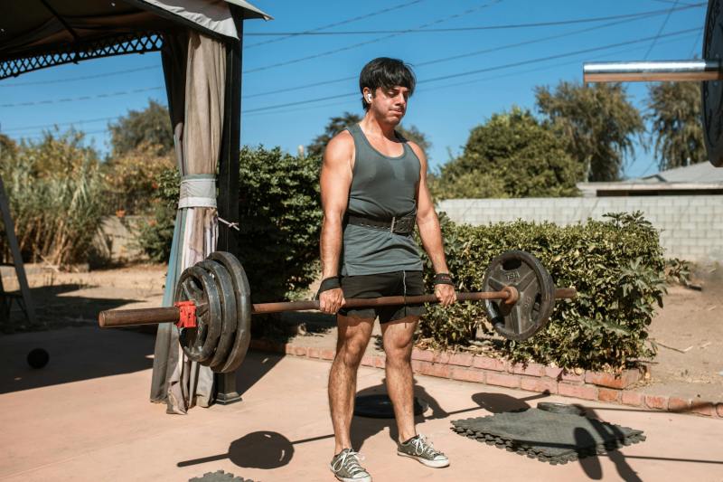 man deadlift barbell outside using lifting straps wrist strap