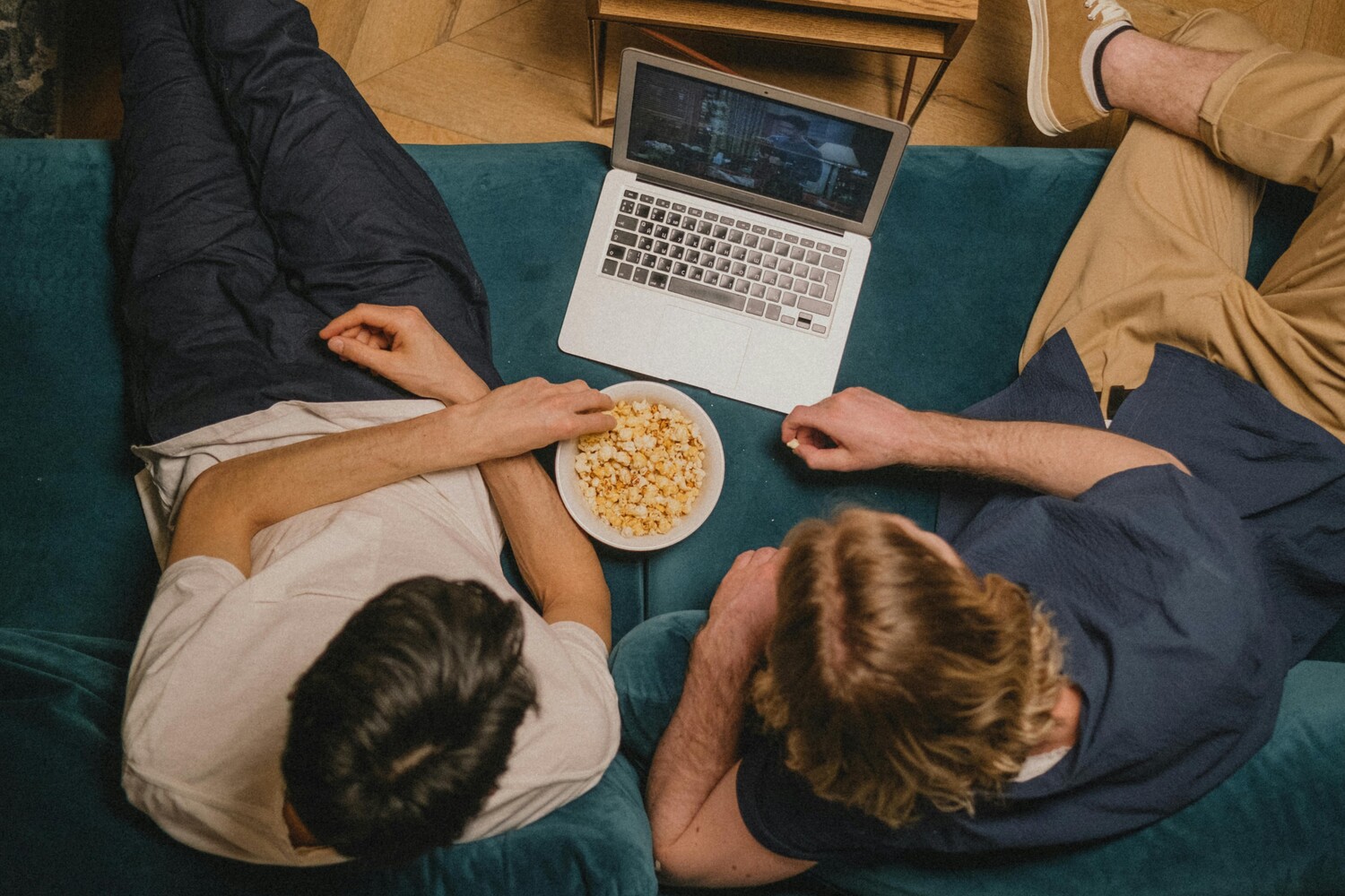 Men eating popcorn while woman is on a laptop