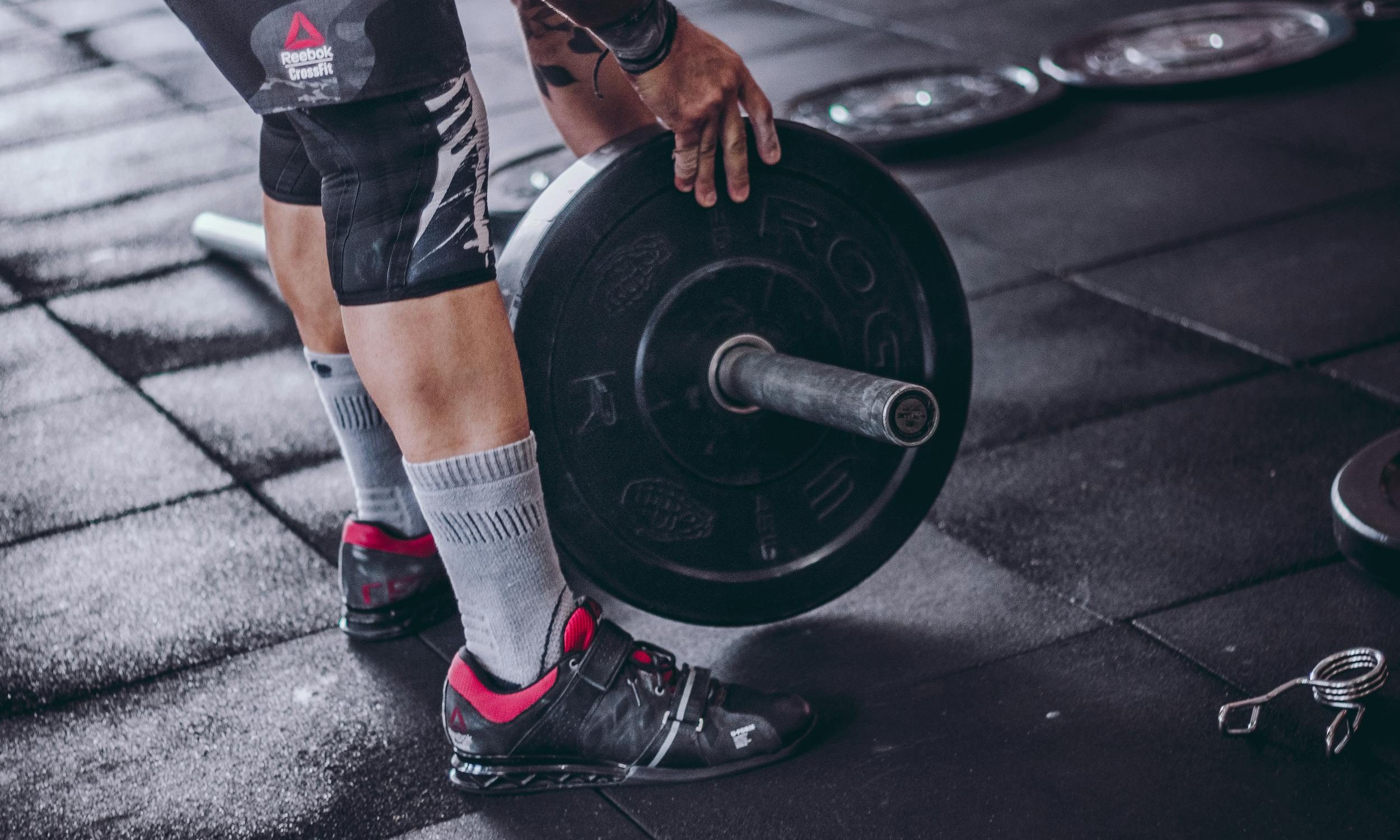 man holding barbell weight leaning down close up
