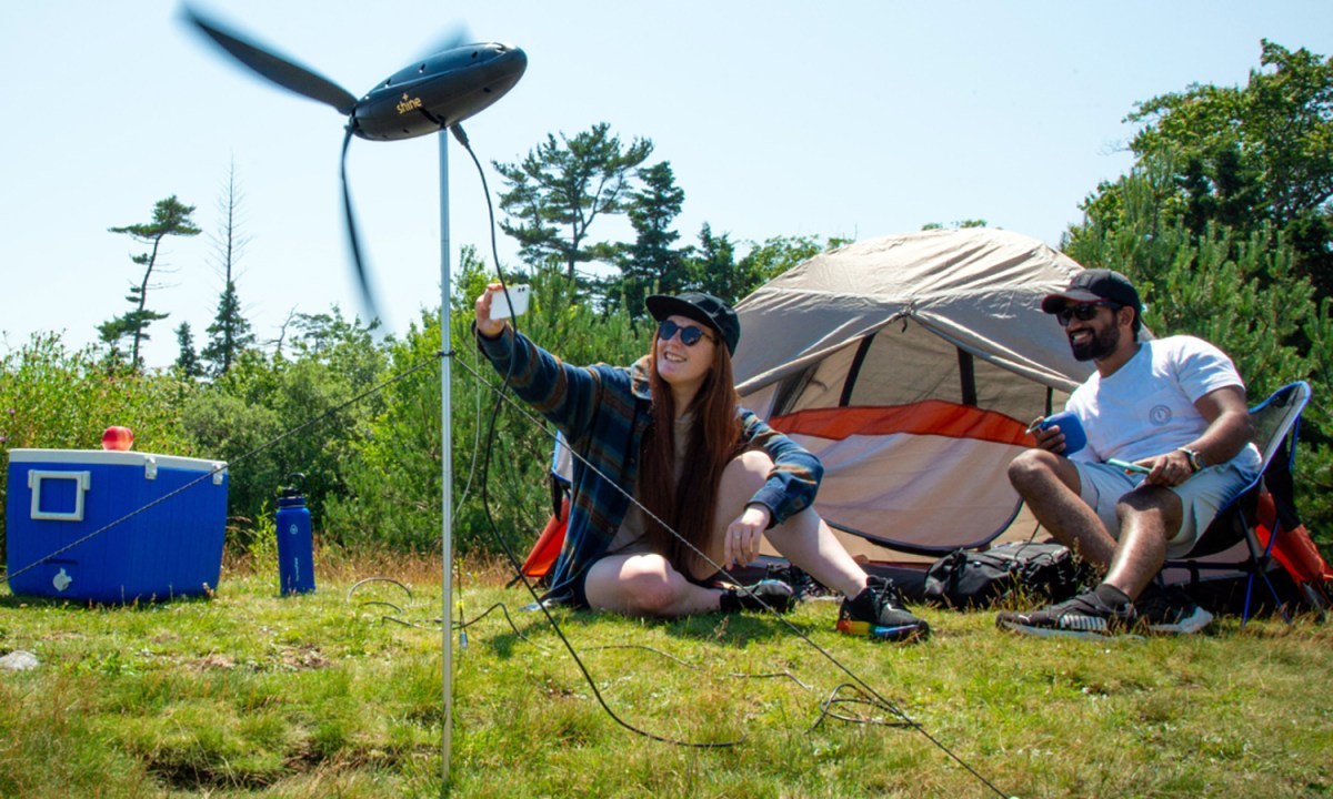 Young couple tent camping with the Shine portable wind turbine setup in the foreground.