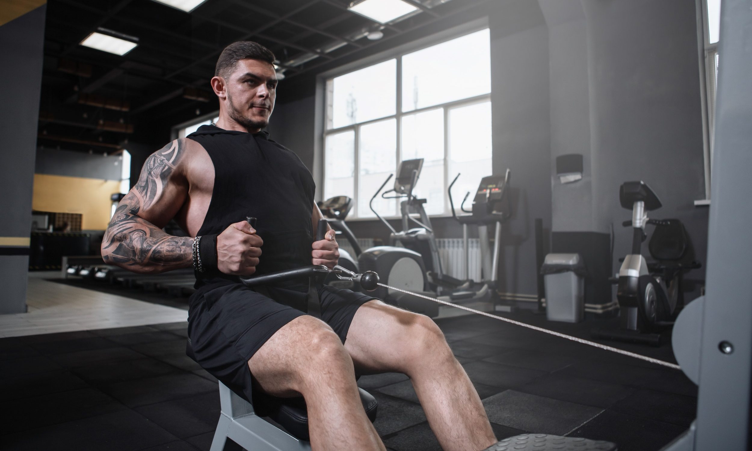 Man sitting in gym doing seated cable row on cable machine