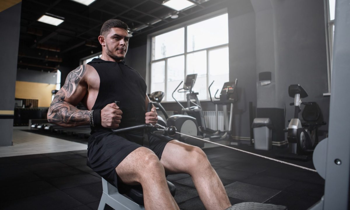 Man sitting in gym doing seated cable row on cable machine