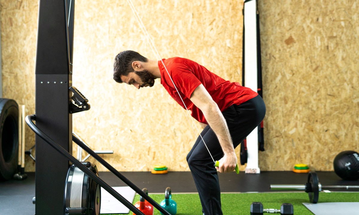 man with red shirt doing SkiErg machine skiing exercise equipment