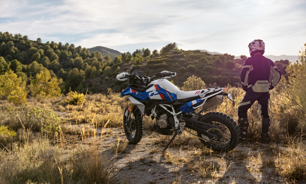 A rider and a BMW Motorrad BMW Concept F 450 GS parked in desert left rear three-quarter view.